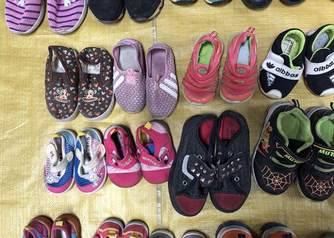 La mano de los niños segundos viste los zapatos/los zapatos usados coloridos de los deportes para el verano